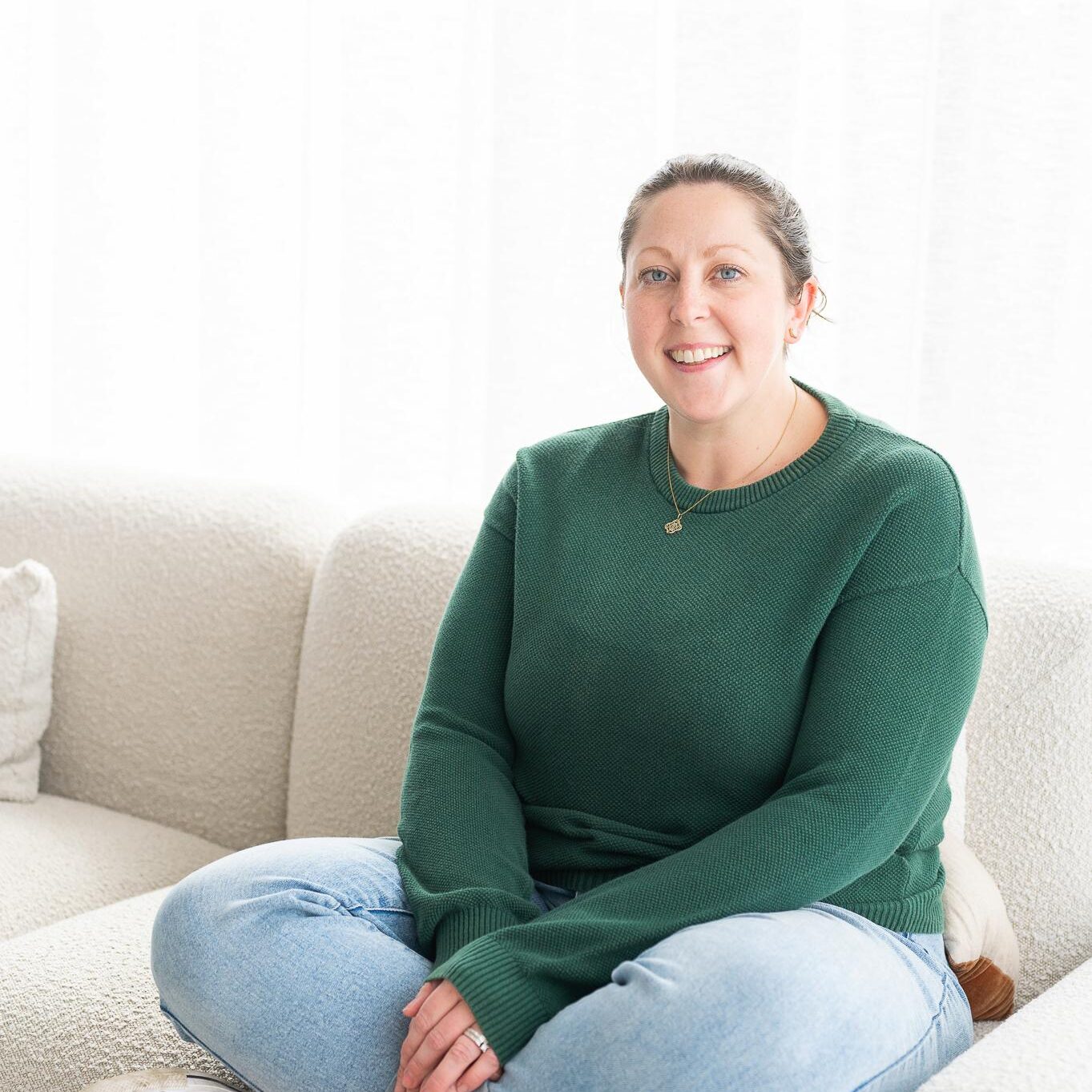 Image of Dacia Davison sitting crosslegged on couch
