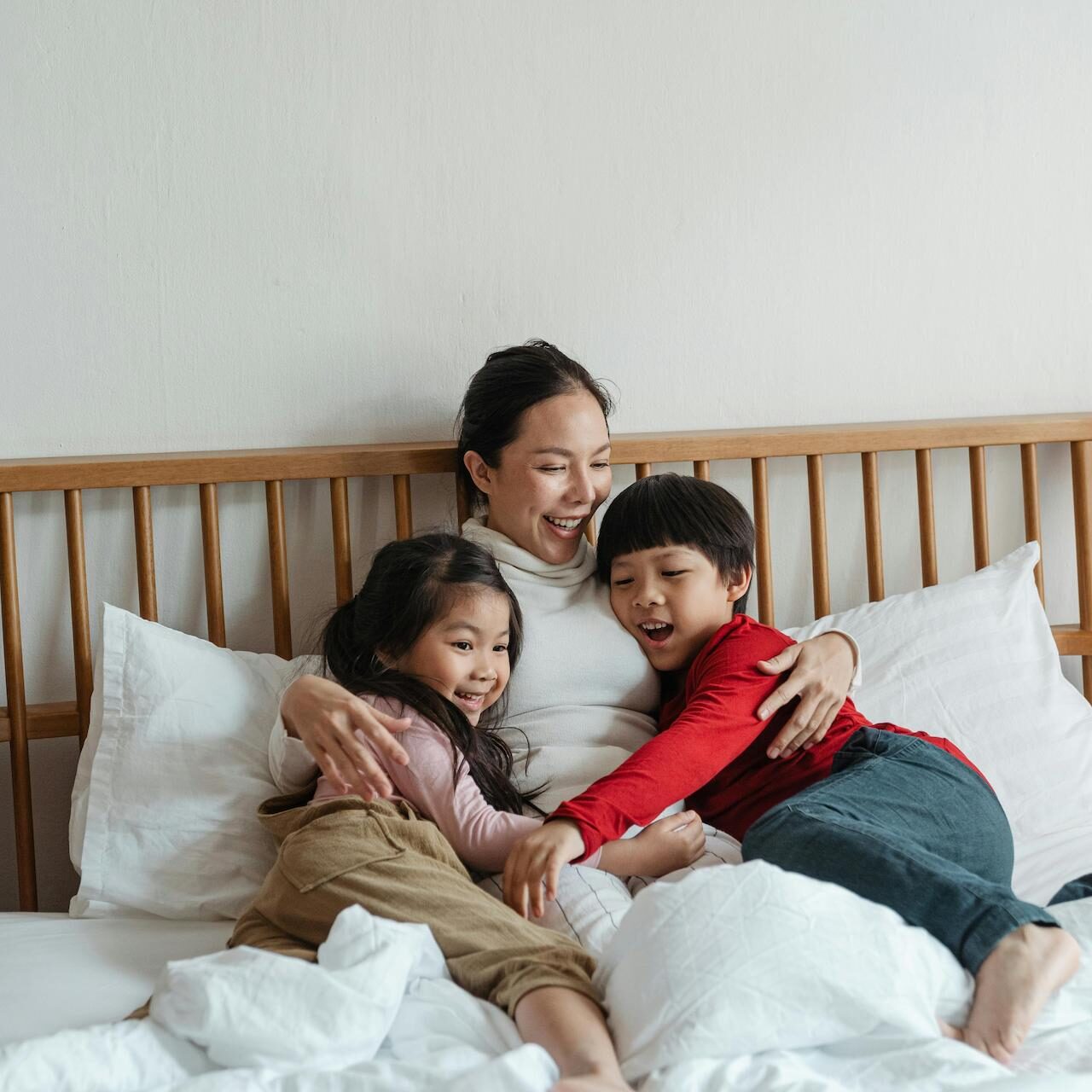 Image of a mother hugging two children in bed